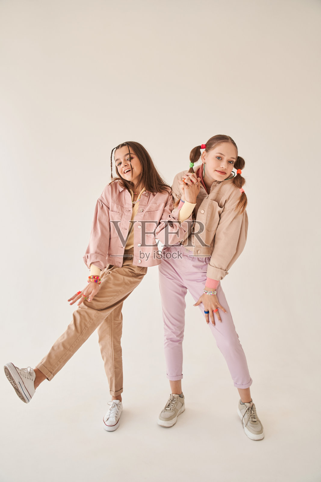 最好的青少年朋友穿着时髦的粉红色衣服，手牵着手照片摄影图片