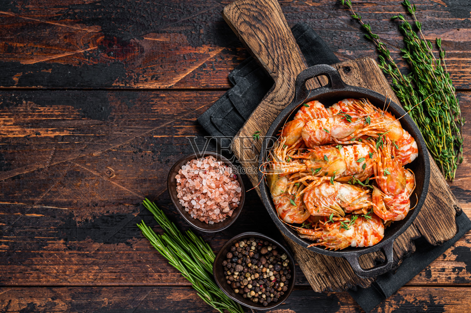 在平底锅里用百里香和迷迭香炒虾。深色木制背景。前视图。本空间照片摄影图片