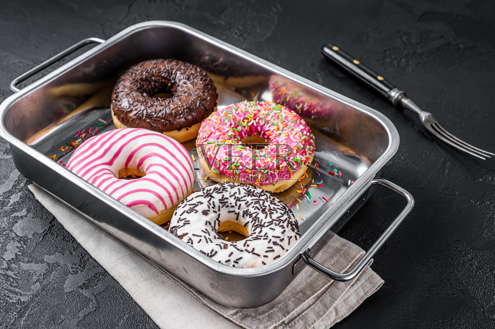 巧克力、粉色和巧克力屑的什锦甜甜圈。黑色背景。俯视图照片摄影图片