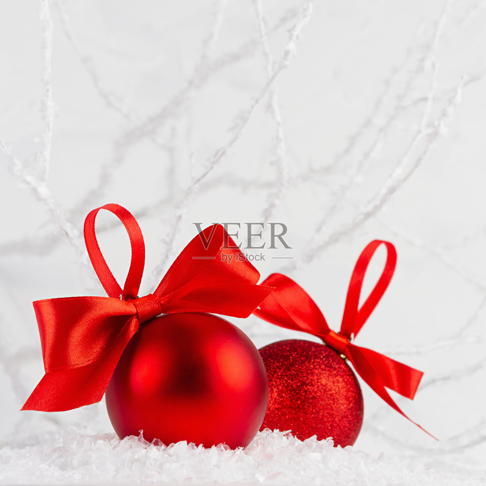 节日新年的背景用两个闪闪发光的亮晶晶的红球配上鲜红的白丝带装饰雪花，霜冻的树枝像冬日森林里的仙女，四方形。圣诞节的背景。照片摄影图片