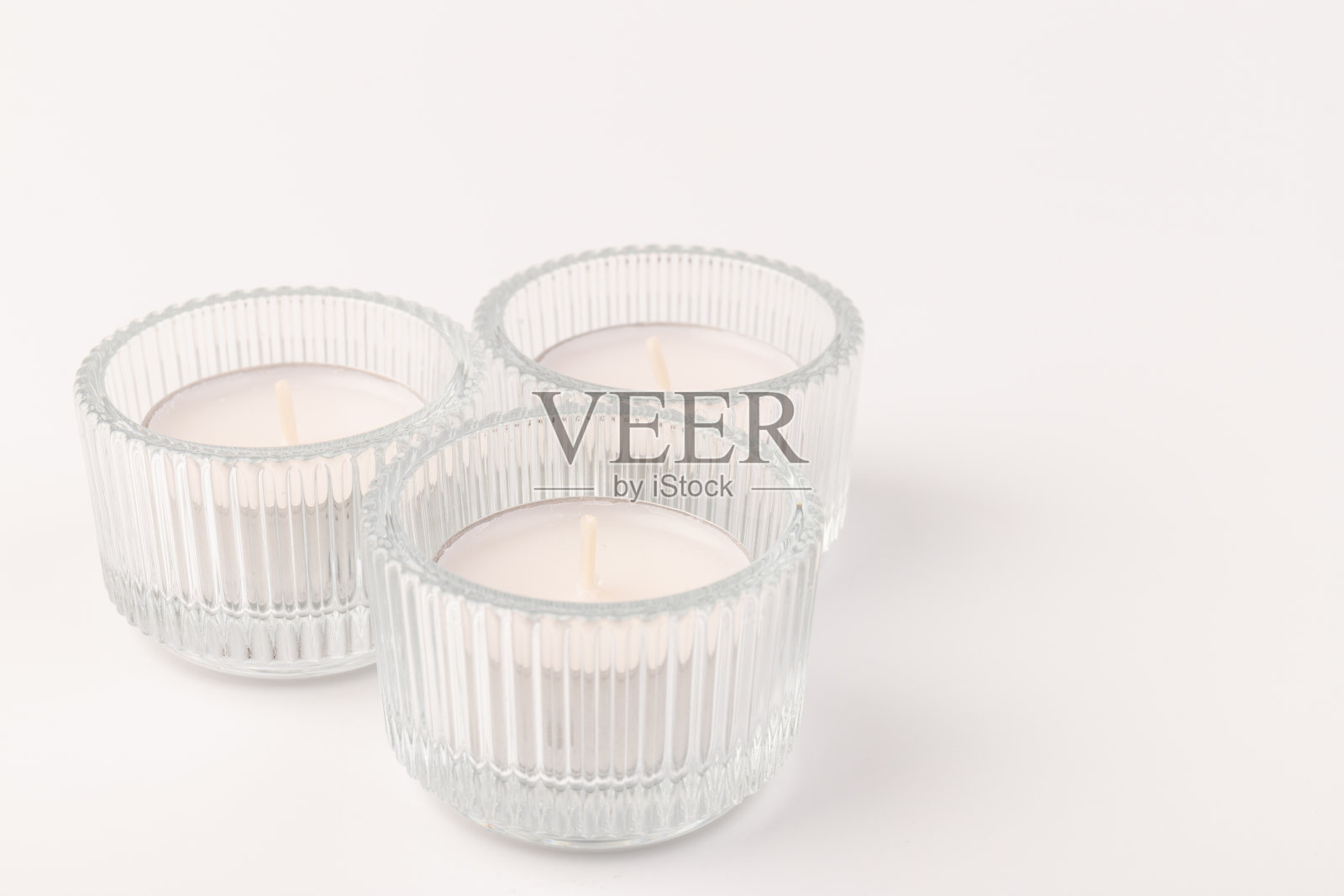 茶蜡烛放在玻璃烛台上，孤立在白色上。空间的文本照片摄影图片