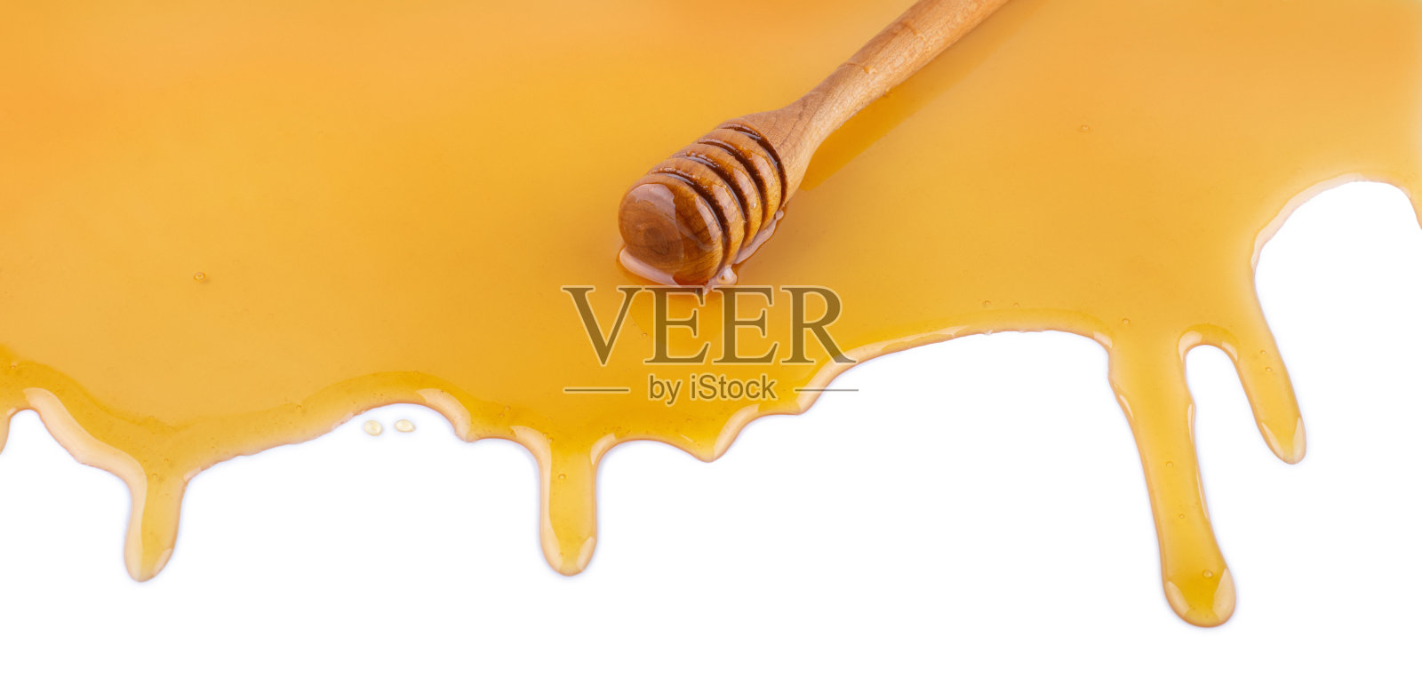 在白色的表面上滴有蜂蜜的蜂蜜勺照片摄影图片