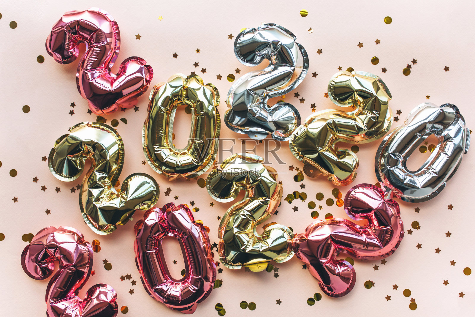 彩色气球由铝箔纸制成，形状为2022，粉红色的背景上有五彩纸屑。庆祝圣诞节，新年和节日的概念。平铺，俯视图。照片摄影图片