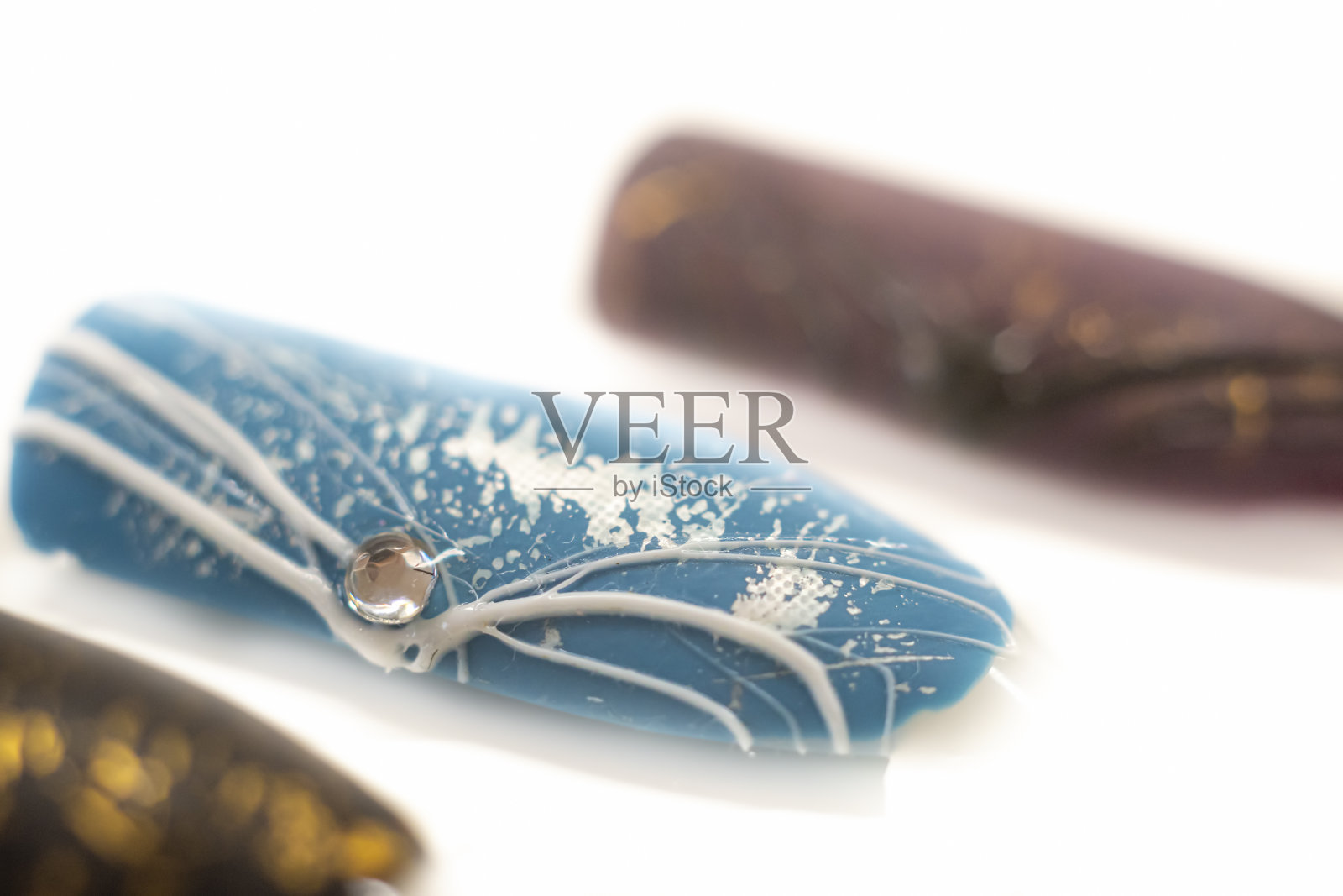 蓝色指甲油上的白色蜘蛛胶照片摄影图片