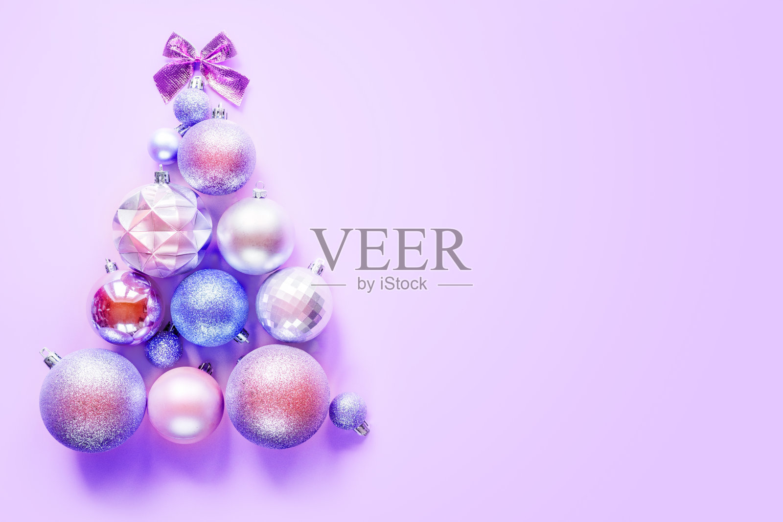 用紫色背景上的圣诞装饰物做成的创新圣诞树照片摄影图片