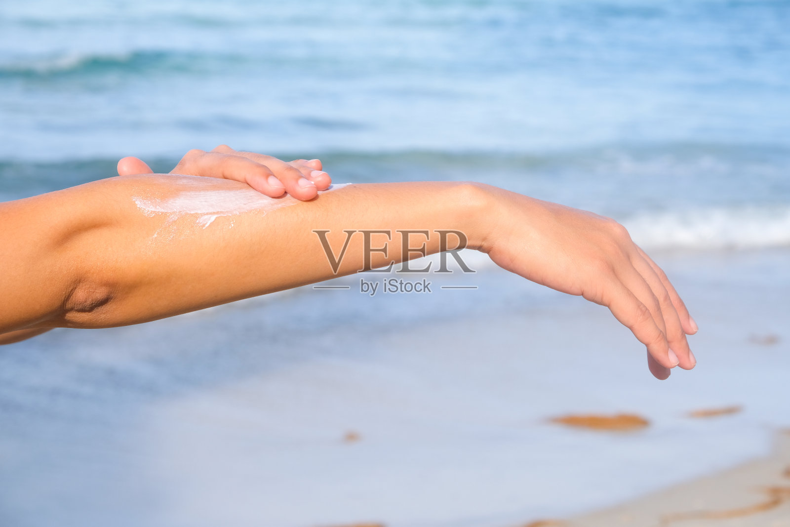 女性拿着防晒霜的手。非常阳光的天空背景。健康理念和皮肤护理照片摄影图片