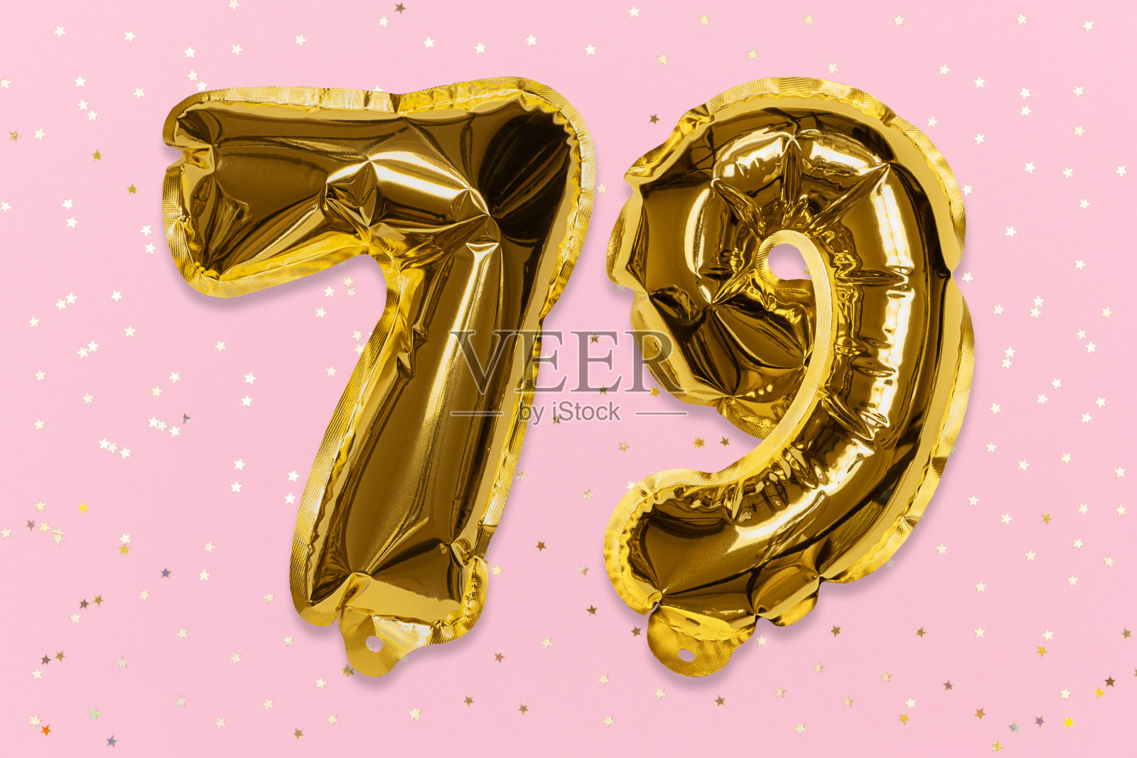 气球的数字是用金箔纸做成的，数字79在带有亮片的粉色背景上。照片摄影图片