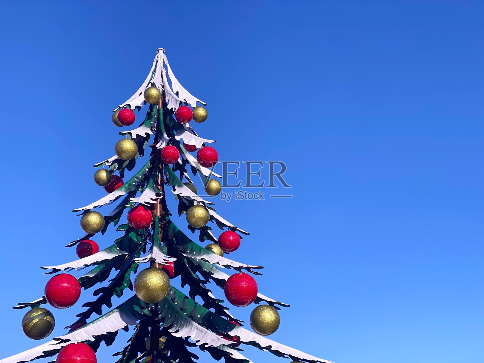 用红色和金色装饰的圣诞树球映衬着蓝色的冬日天空。照片摄影图片