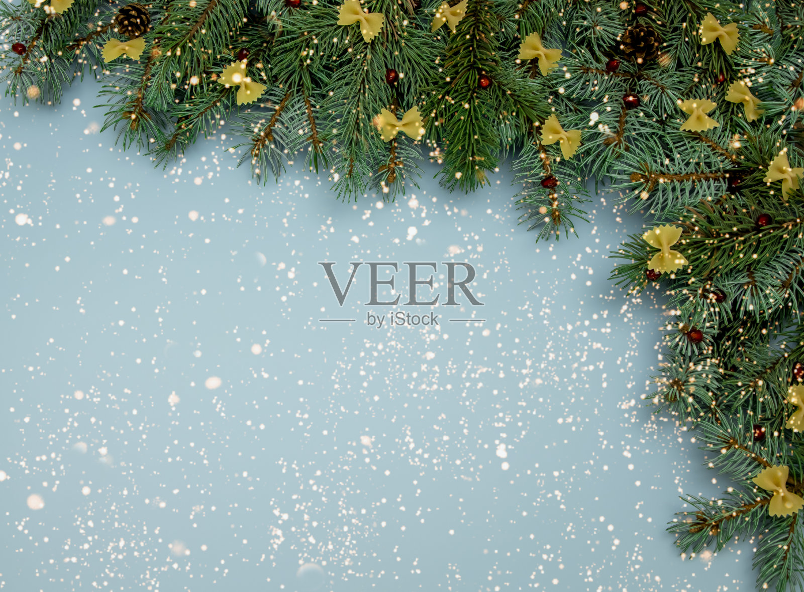 top view on blue Christmas background and falling snow with冷杉树枝和意大利面弓。健康饮食，适当营养，地方文字，广告和祝贺，明信片照片摄影图片