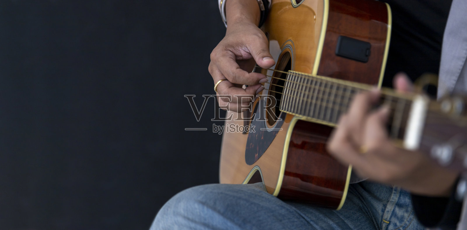 吉他手在黑色背景下弹奏原声吉他的特写镜头照片摄影图片