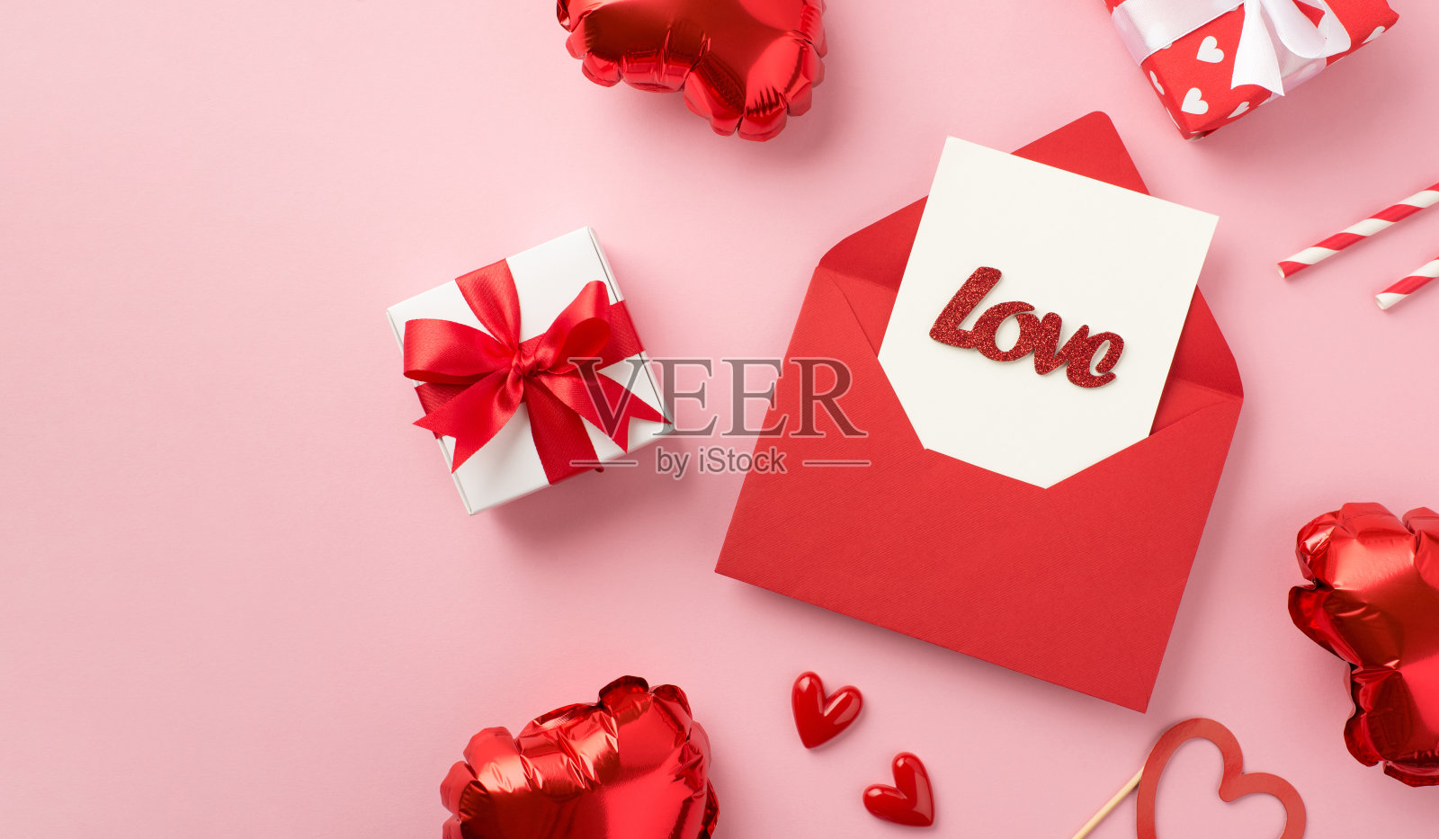 打开红色信封与卡片和题字爱小心礼品盒吸管和心形气球在孤立的淡粉色背景照片摄影图片