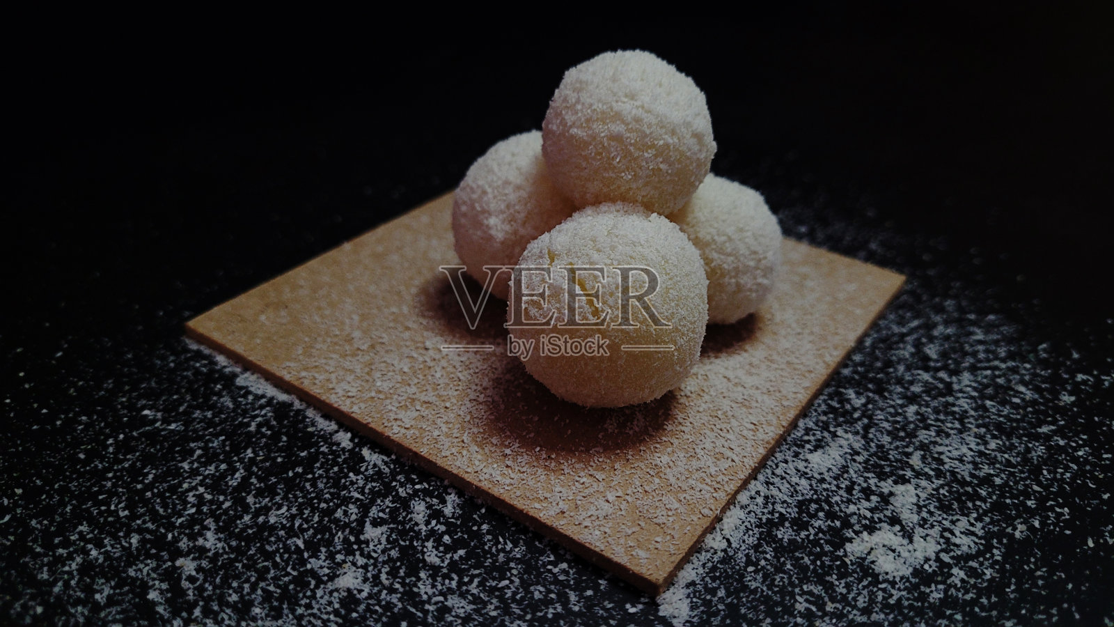 黑色背景木板上的雪球圣诞糖果，椰子屑，牛奶糖果的特写，米浆韩国甜点，健康甜点，椰子汁糖果，素食甜点照片摄影图片