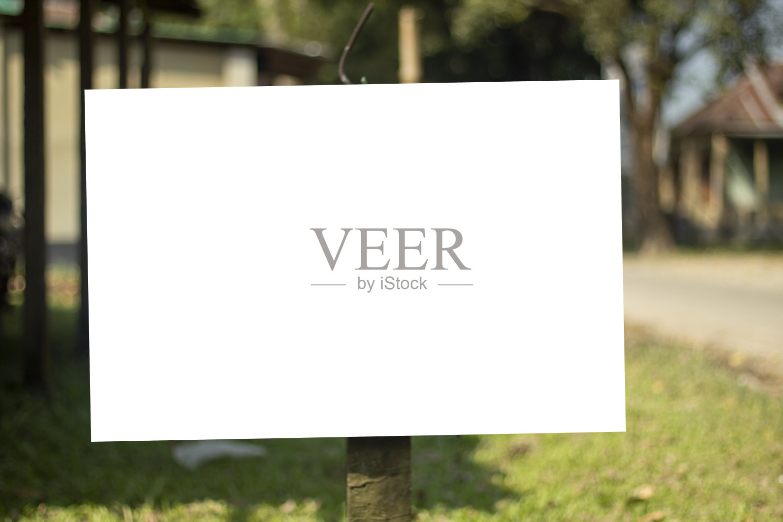 一个巨大的白色标牌，挂着一根杆子，后面的背景模糊了。照片摄影图片