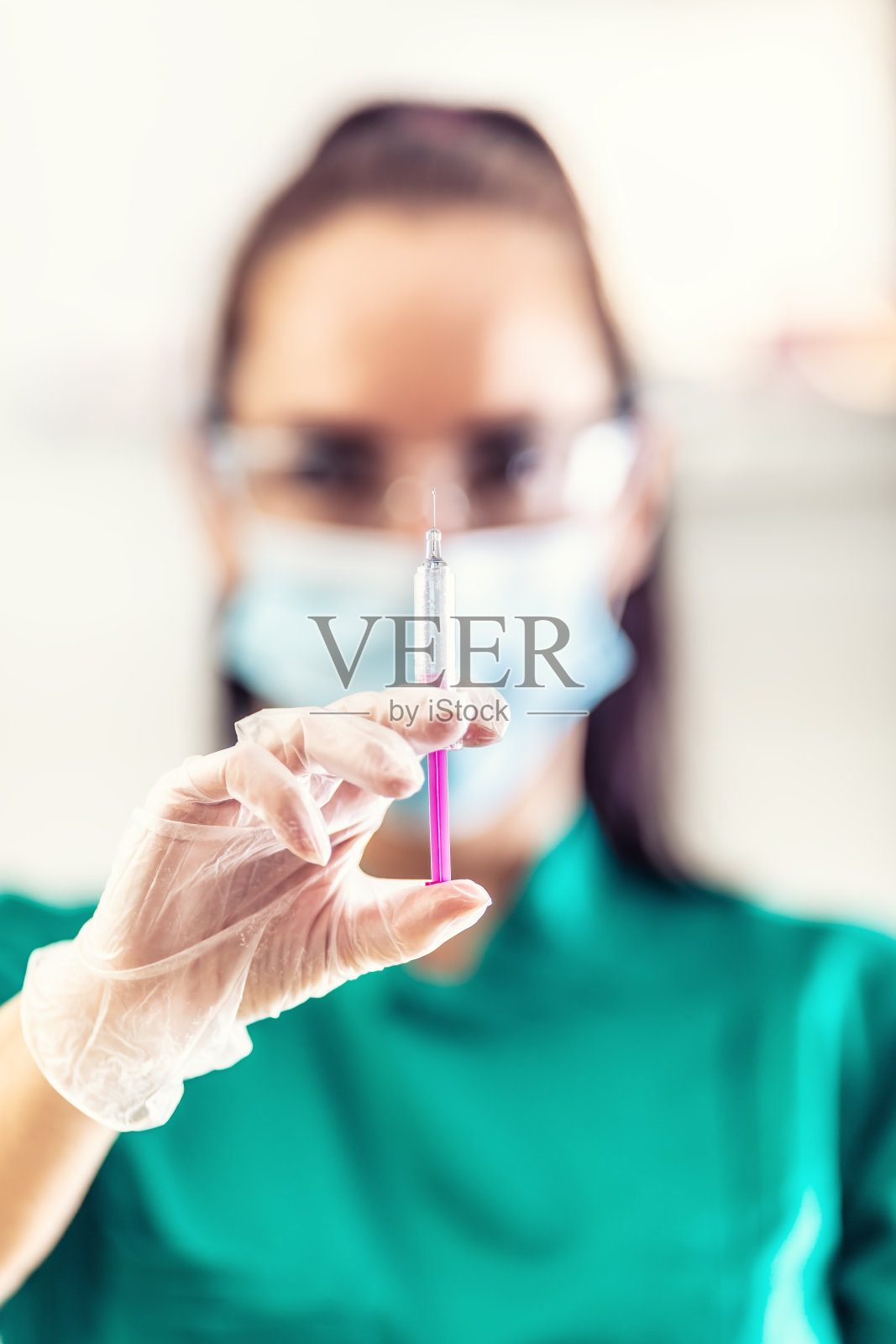 医生在防护口罩、手套和护目镜中测试疫苗注射的细节。照片摄影图片