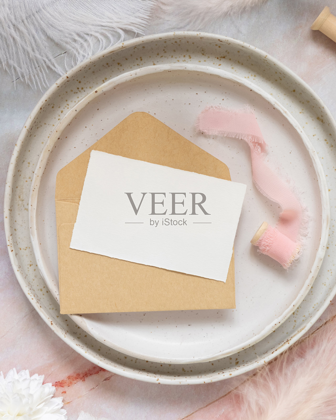 婚礼桌的地方与卡片超过信封附近的鲜花和羽毛，模型照片摄影图片