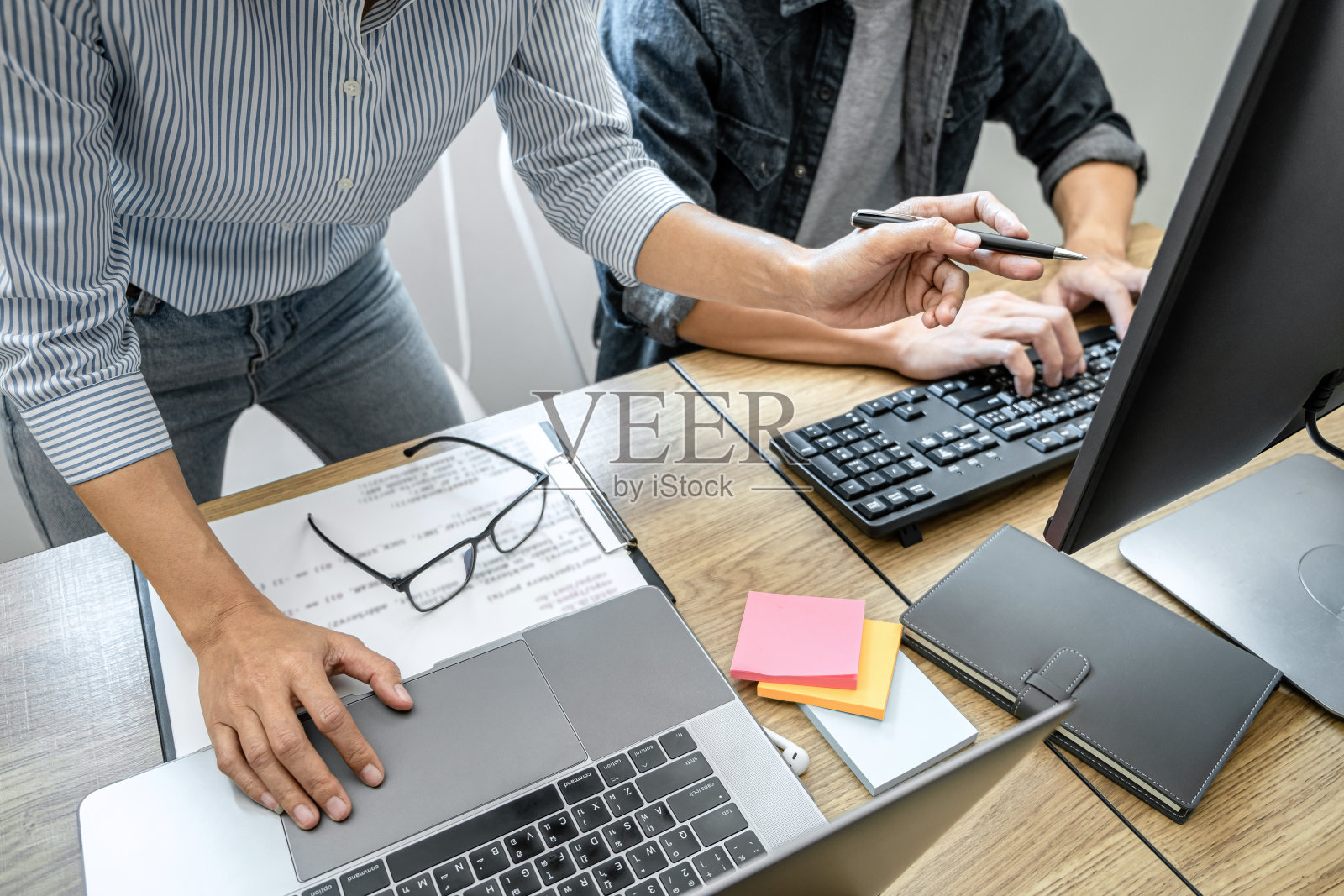 两名专业程序员在公司的台式机上合作开发网站项目，编码和输入数据代码，用HTML, PHP和javascript编程照片摄影图片