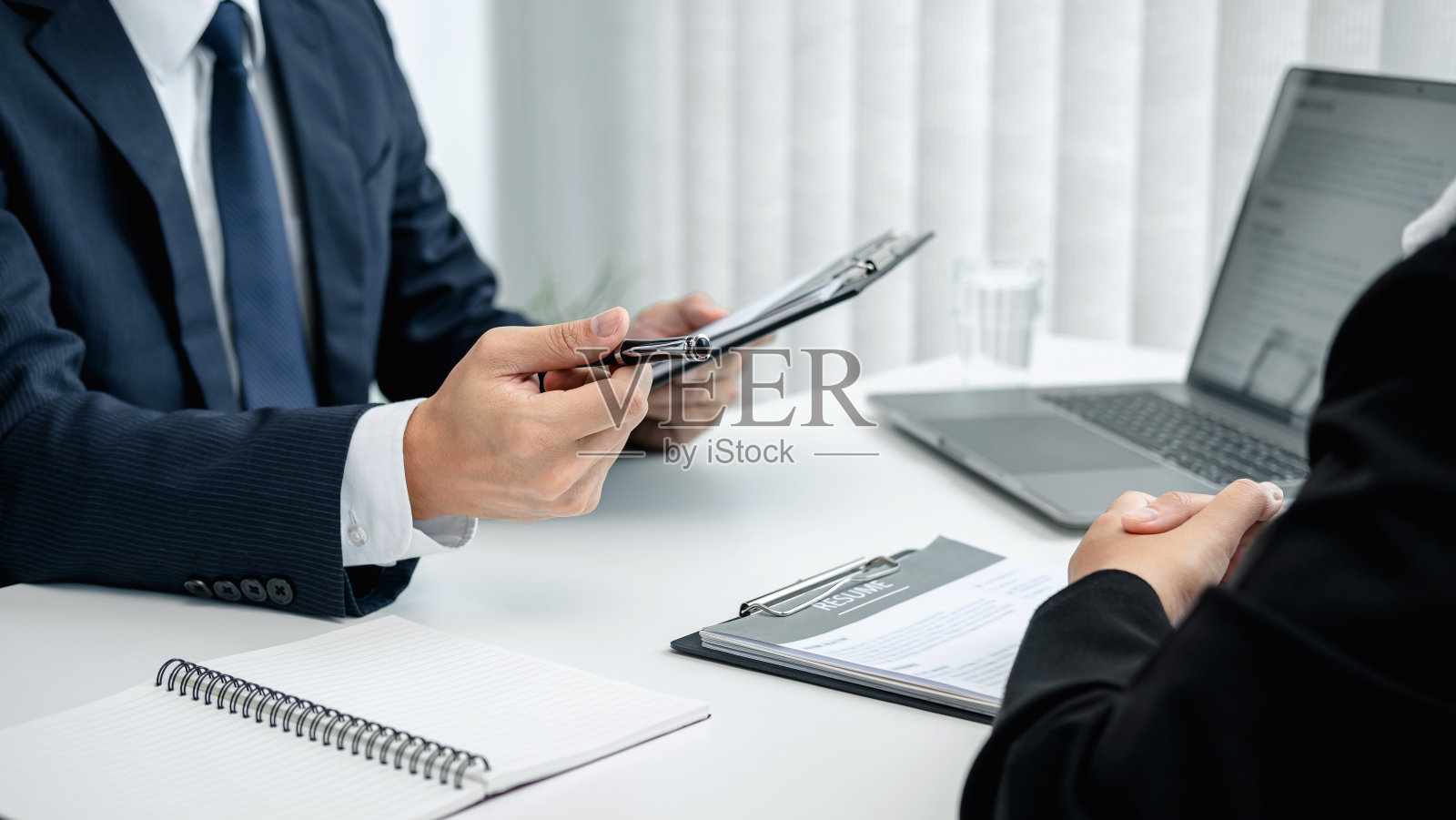 西装男老板拿着应聘者的简历看她的简介，问应聘者问题照片摄影图片