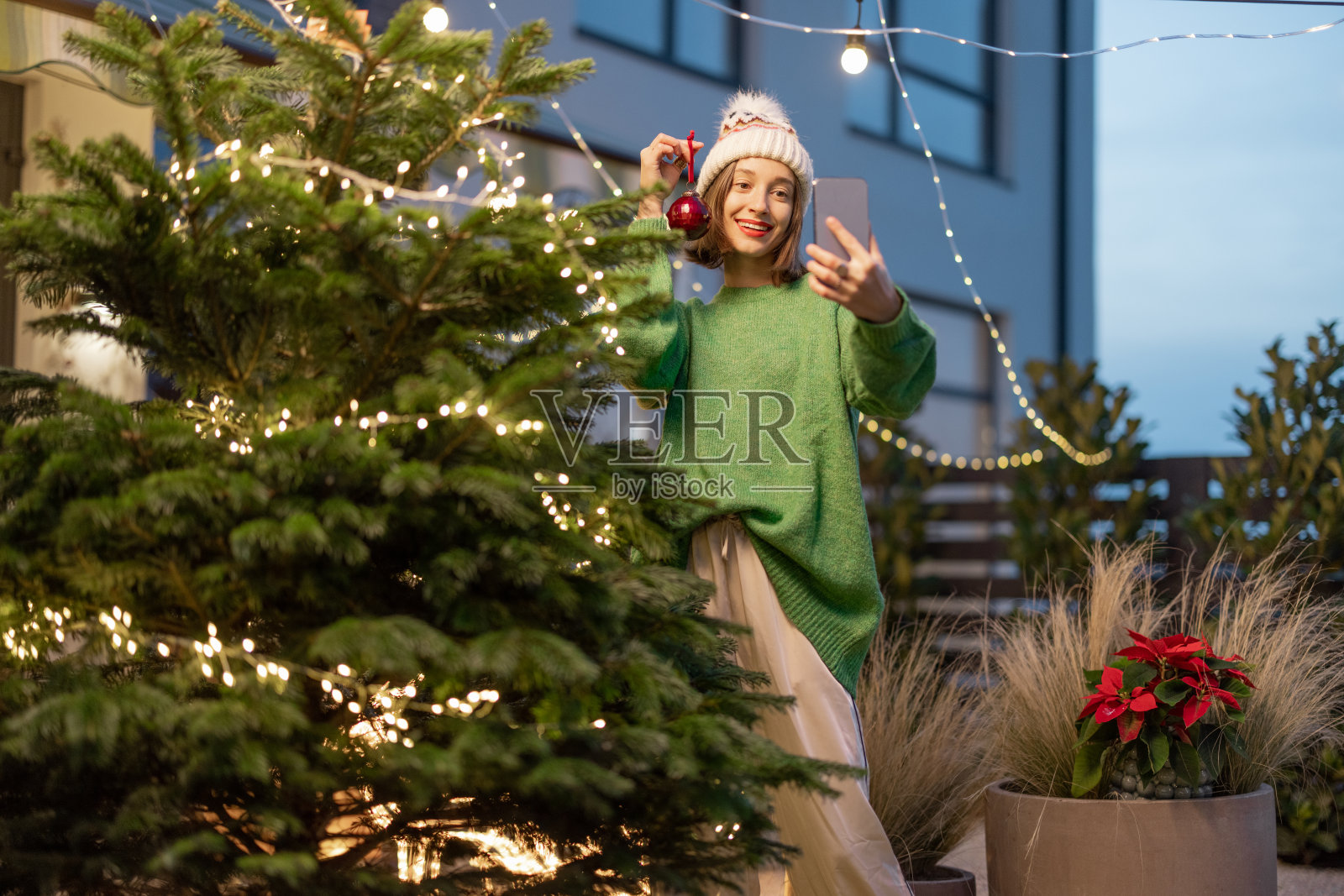 女人在后院装饰圣诞树照片摄影图片