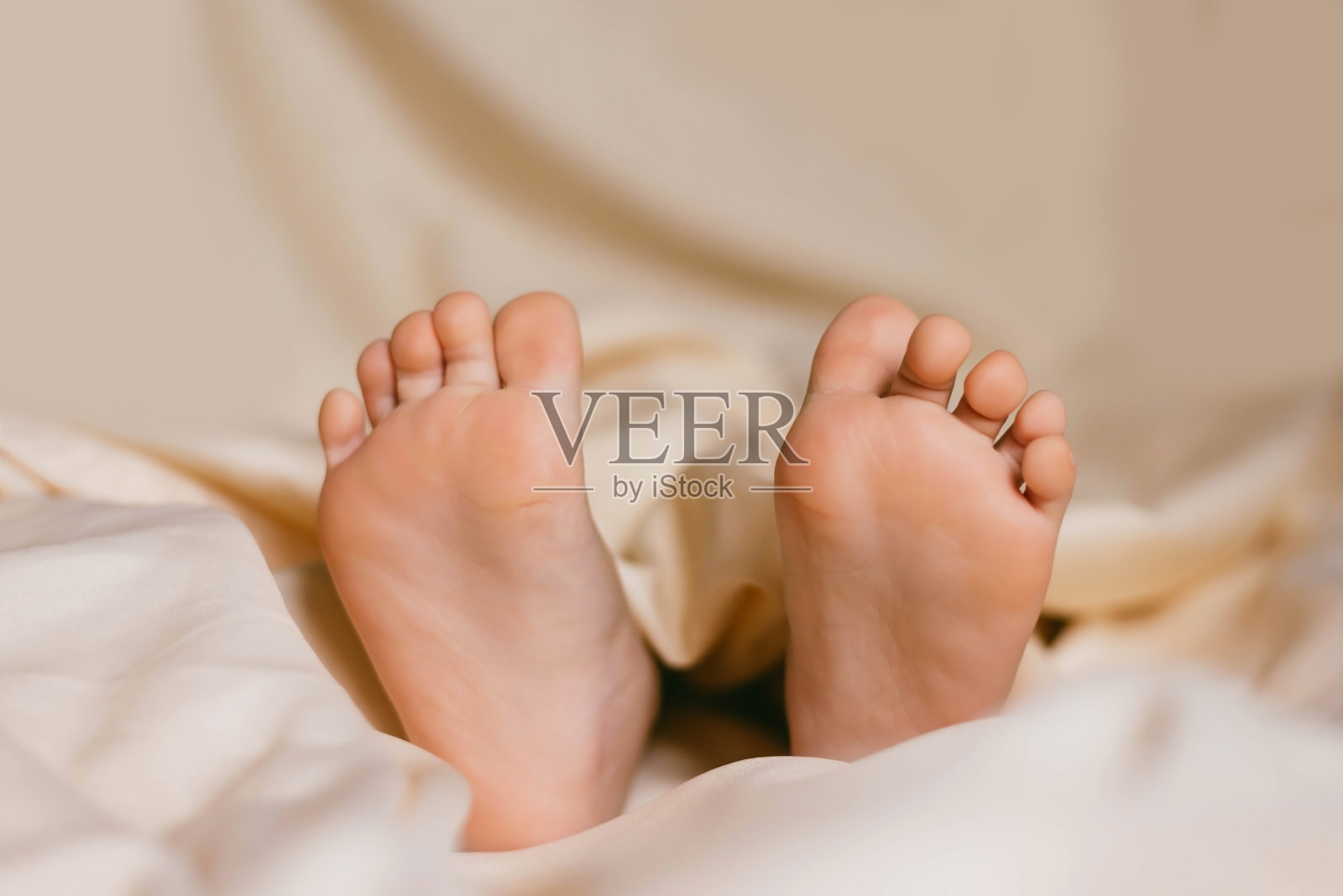 孩子的脚踩在白色的床上。婴儿在他的婴儿床里睡觉。睡眠对婴儿的重要性。睡眠模式婴儿3岁。照片摄影图片