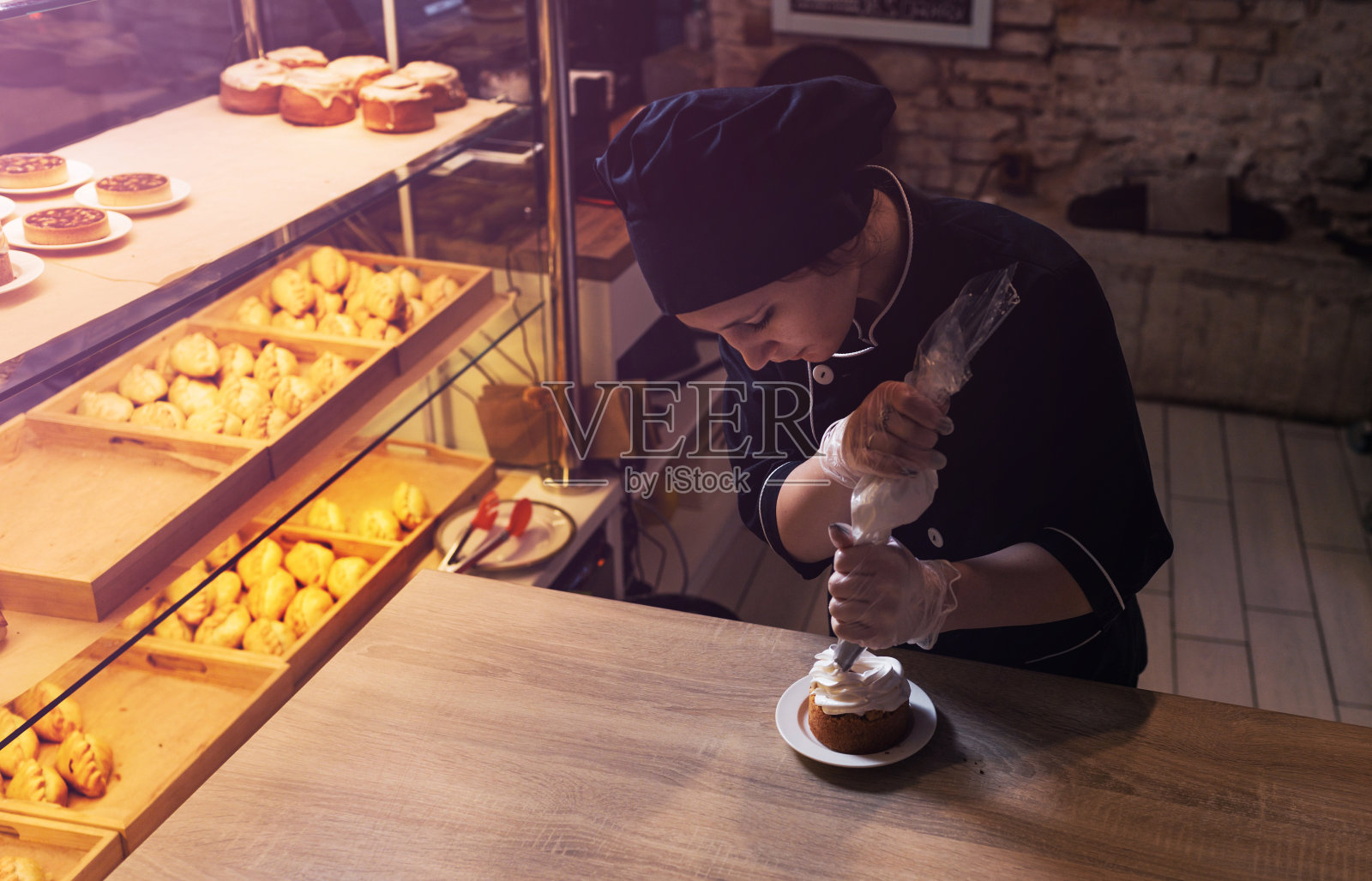 一个糕点师女孩用装着蛋白质奶油的糕点袋装饰酥饼蛋糕，把奶油挤出来。特写镜头照片摄影图片