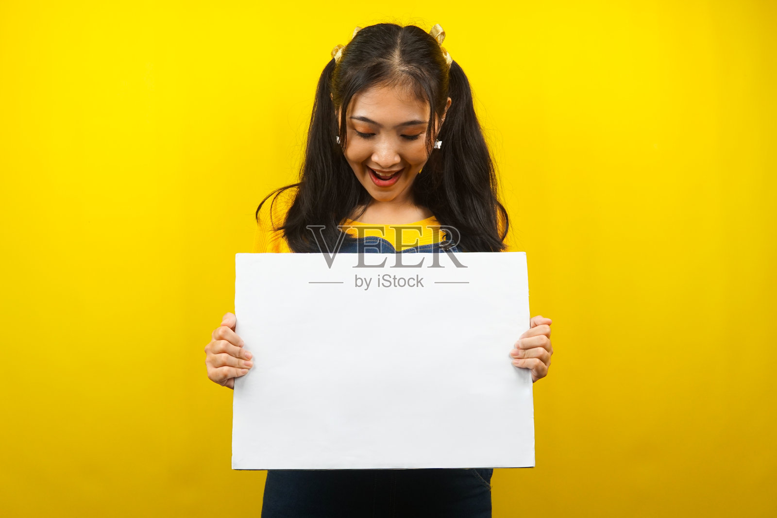 漂亮可爱的年轻女子欢快地拿着空白的空横幅、广告牌、白板、白板招牌、白色广告牌，在文案空间展示东西，促销照片摄影图片