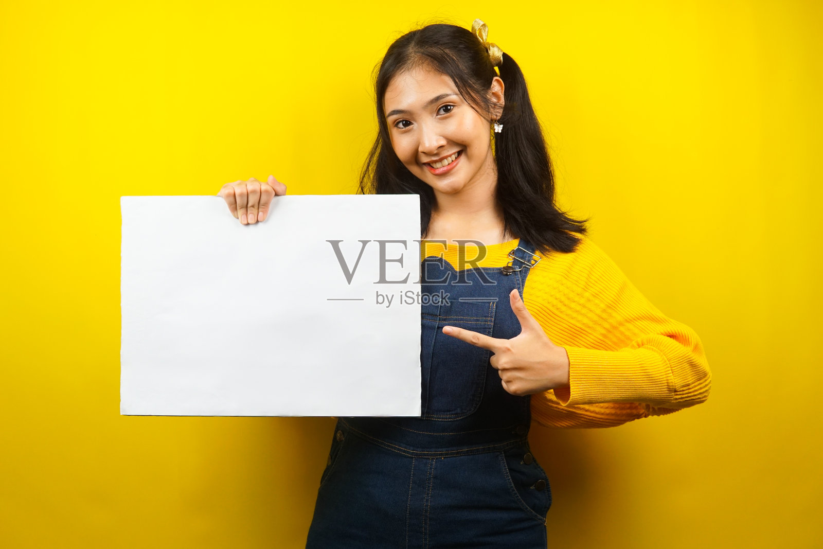 漂亮可爱的年轻女子欢快地拿着空白的空横幅、广告牌、白板、白板招牌、白色广告牌，在文案空间展示东西，促销照片摄影图片