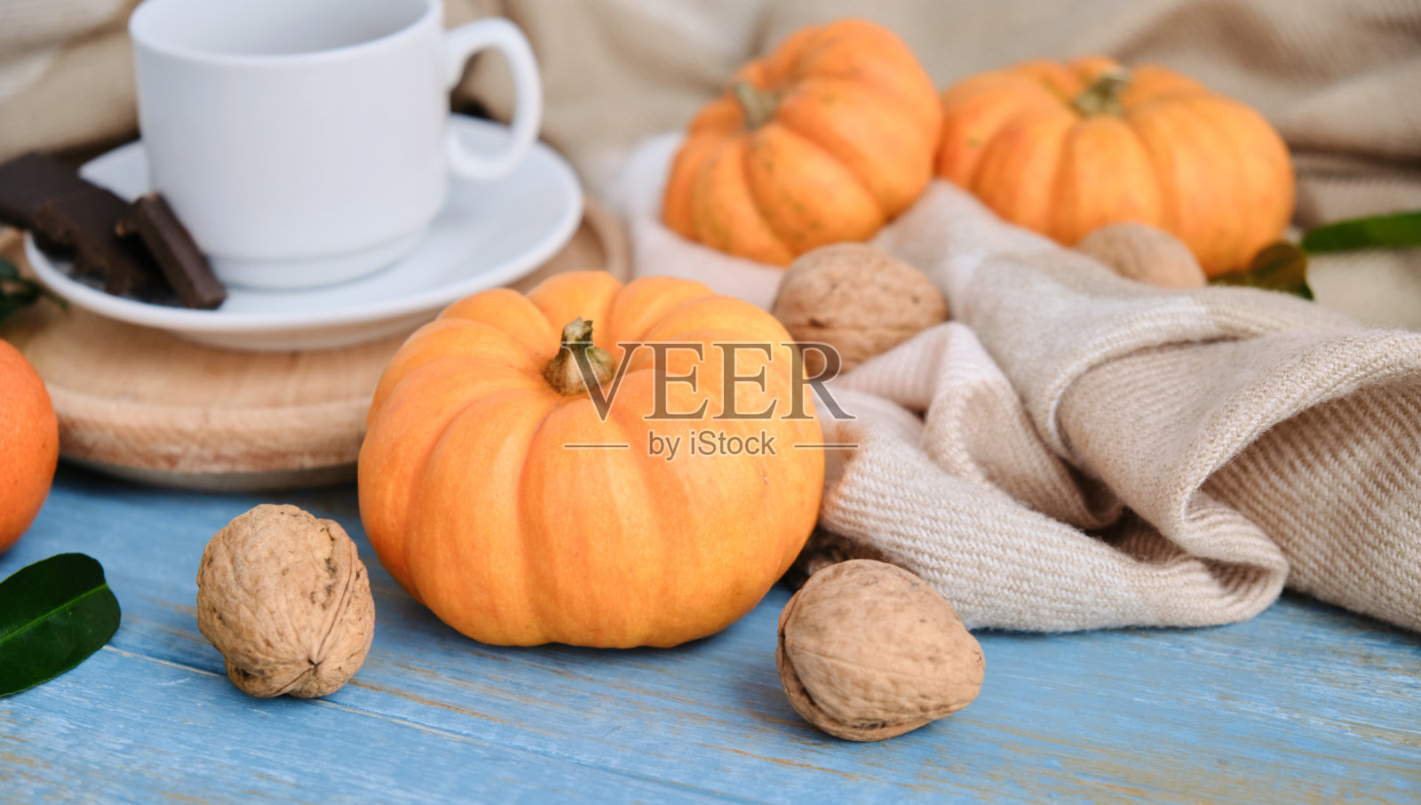 秋天平铺背景。南瓜，苹果，坚果，树叶，杯子和毛衣的木制背景。照片摄影图片
