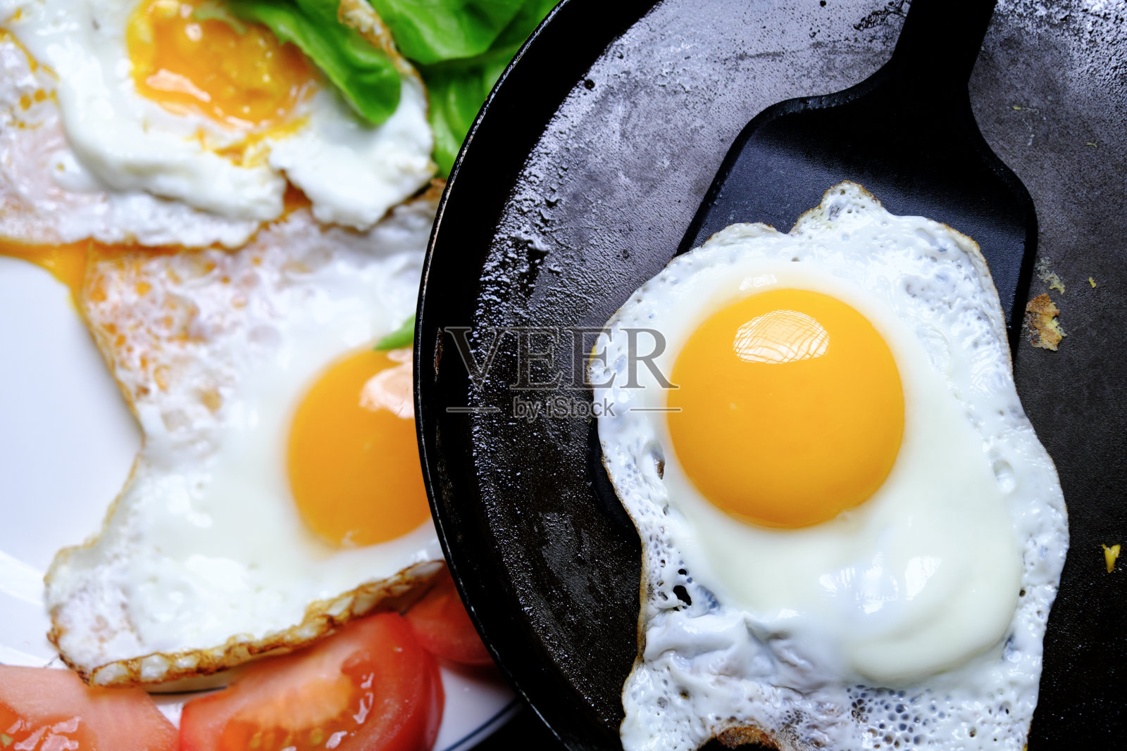 将煎蛋从煎锅中取出放入盘中照片摄影图片