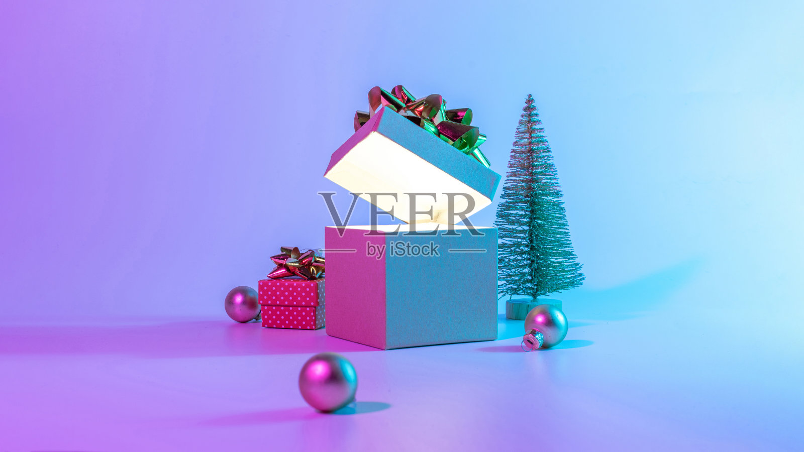 霓虹圣诞冬季背景。打开圣诞礼品盒，用发光的灯，最小的树。节日装饰珠在霓虹灯抽象梯度背景。新年快乐拷贝空间。照片摄影图片