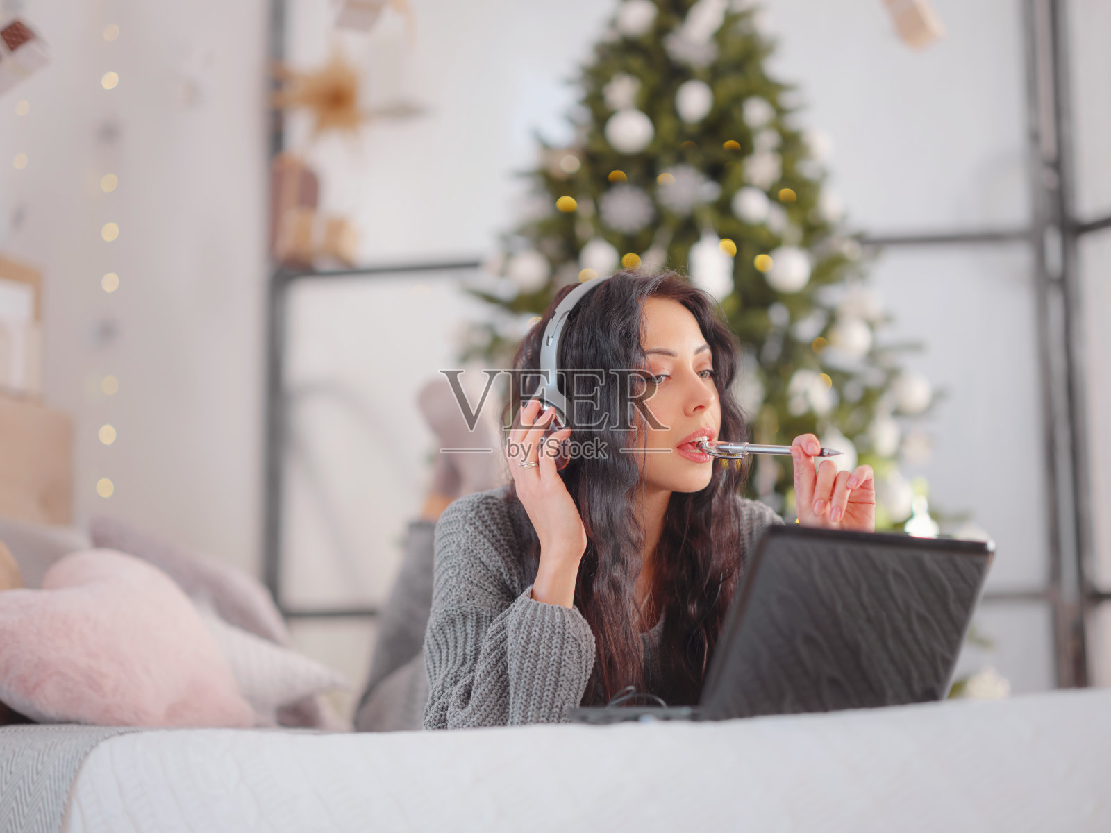 女人在舒适的灰色针织毛衣在床上使用笔记本电脑，圣诞节假期照片摄影图片