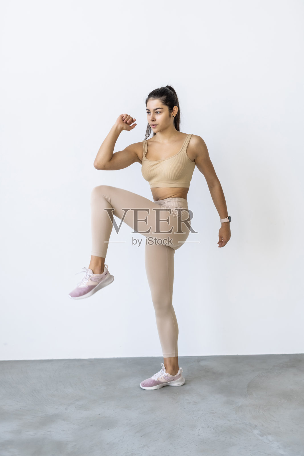 年轻美丽的褐发女郎在白色背景上做踏板健身操照片摄影图片