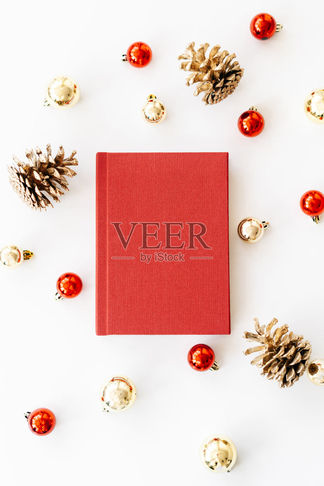 一本白色背景的红色书，里面有礼物、圣诞礼帽和圣诞玩具。圣诞节的概念照片摄影图片