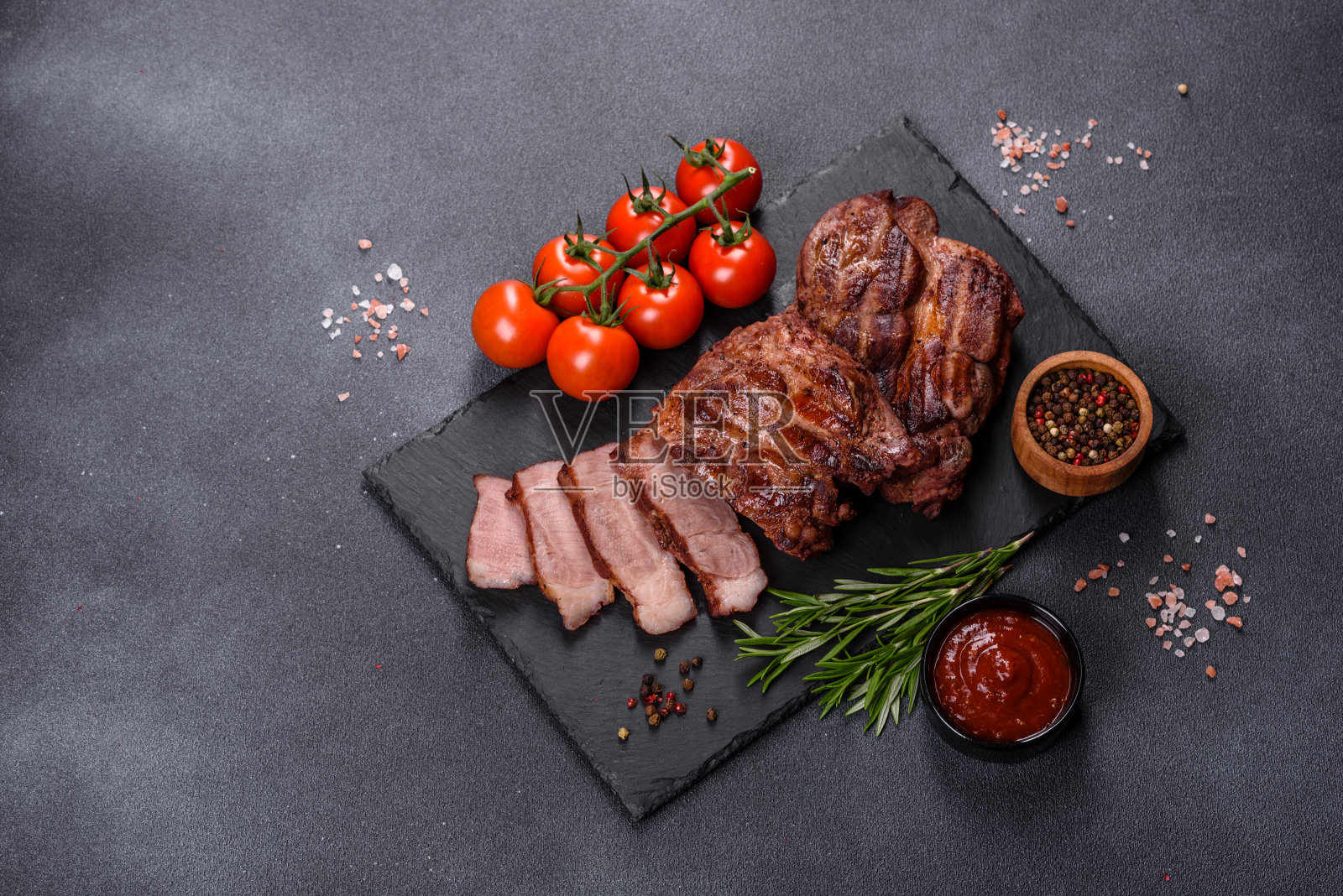 黑色切菜板上放有香料的烤牛排照片摄影图片