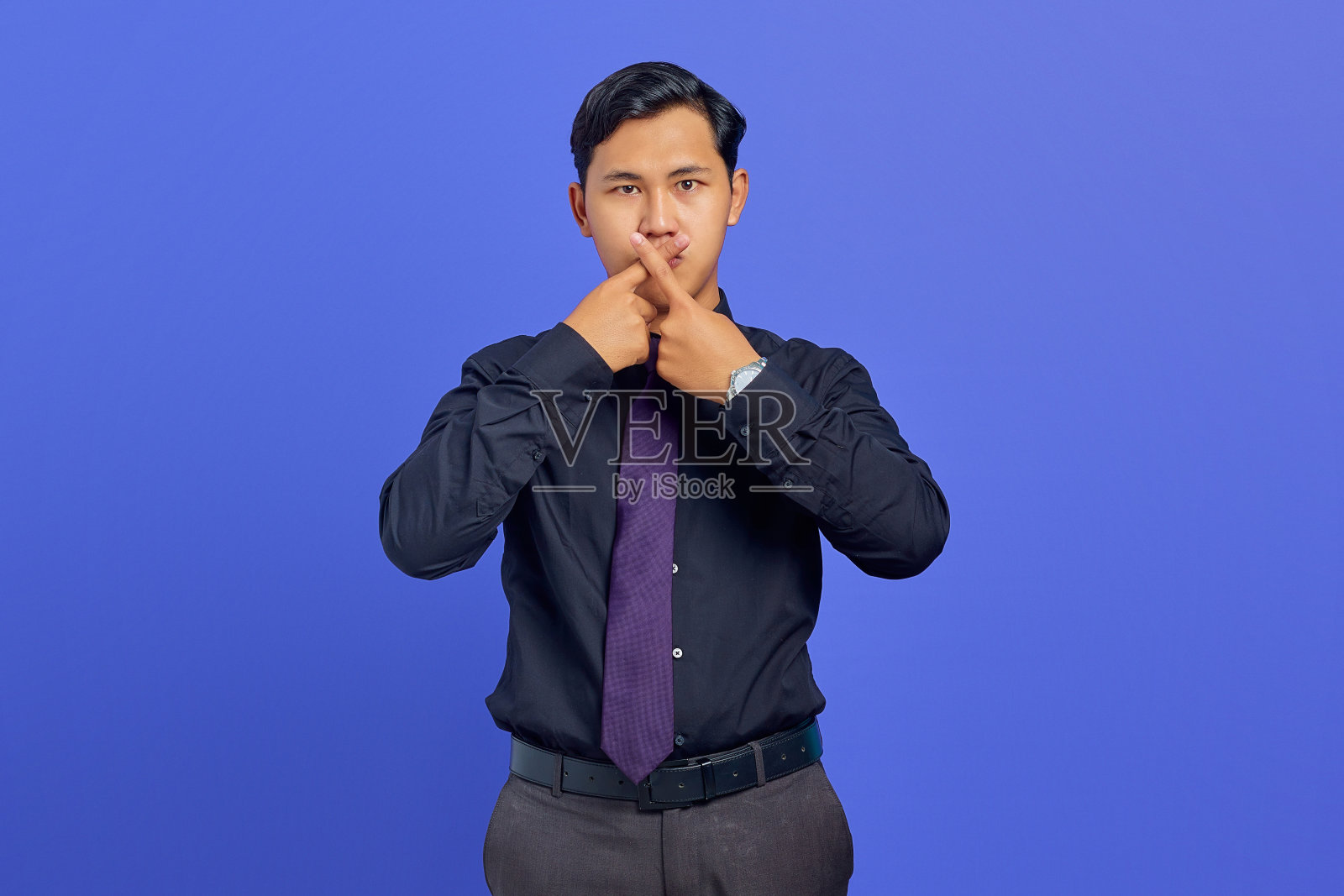 严肃的年轻英俊的商人交叉手指，并在紫色背景上表示拒绝的姿态照片摄影图片