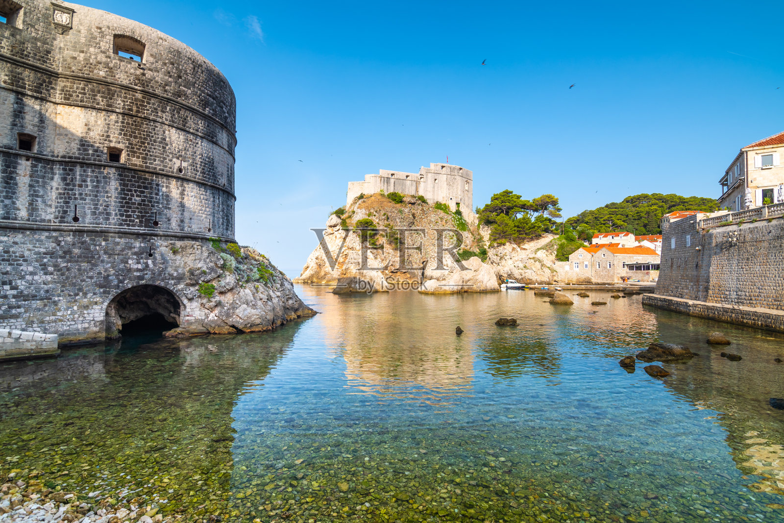 杜布罗夫尼克老城附近的小水湾。靠近小港口的古老堡垒洛夫里耶纳克有船只。阳光明媚的一天。照片摄影图片
