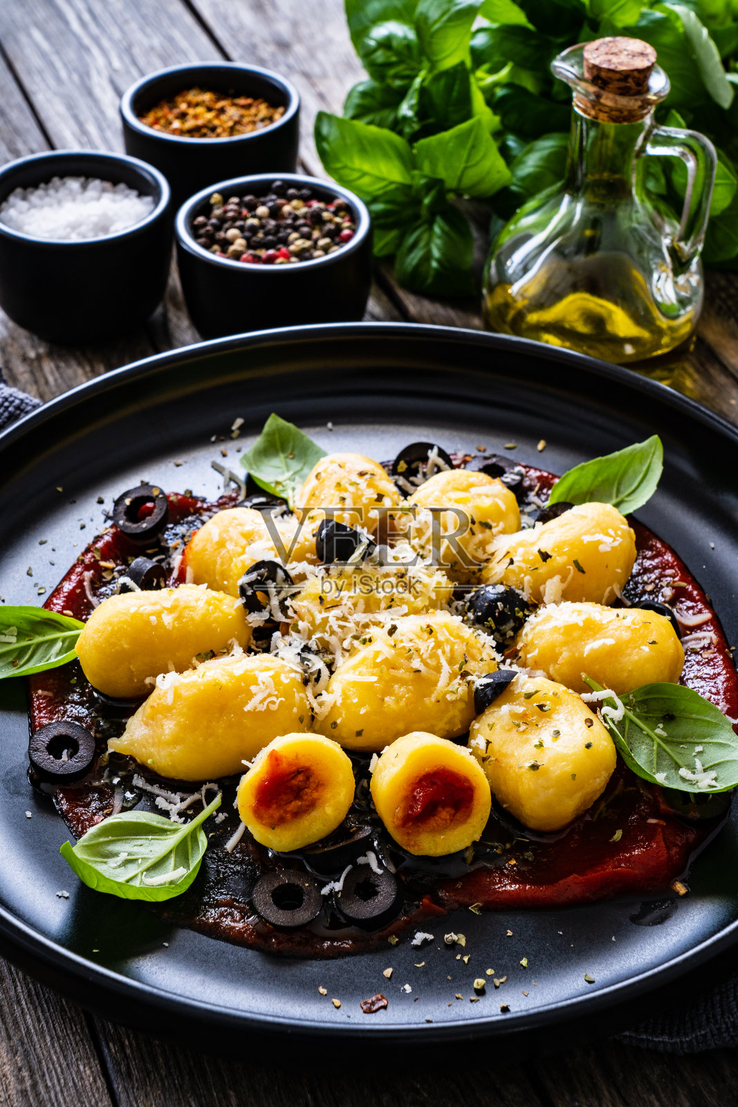 木桌上的土豆汤圆，里面塞满了番茄、帕尔马干酪、黑橄榄和罗勒照片摄影图片