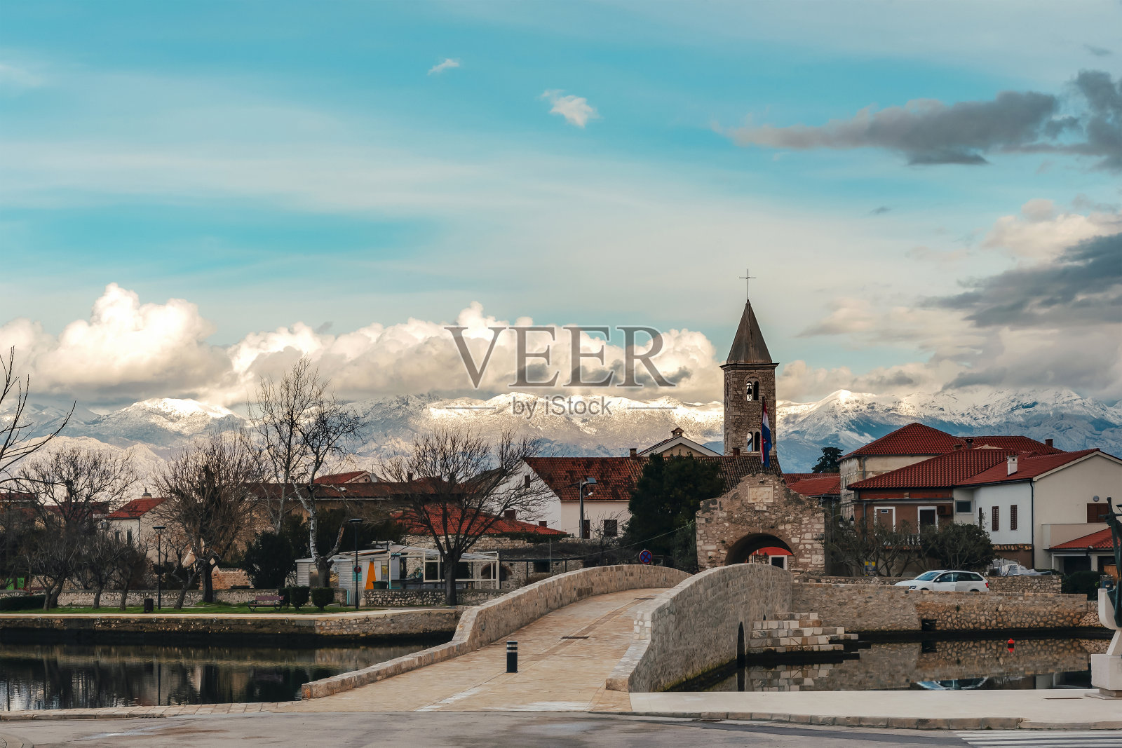 横跨海峡和克罗地亚历史城市宁入口的桥梁。Velebit山的雪峰。美丽的景观照片摄影图片