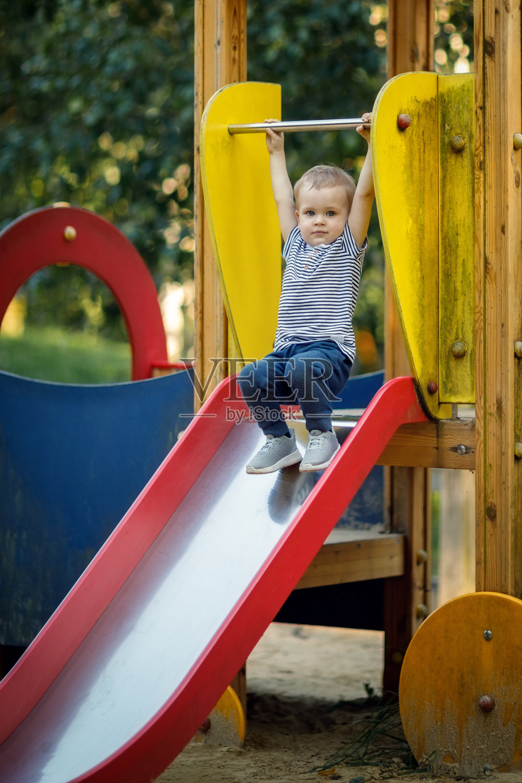 一个小男孩在公园里的彩色滑梯上照片摄影图片