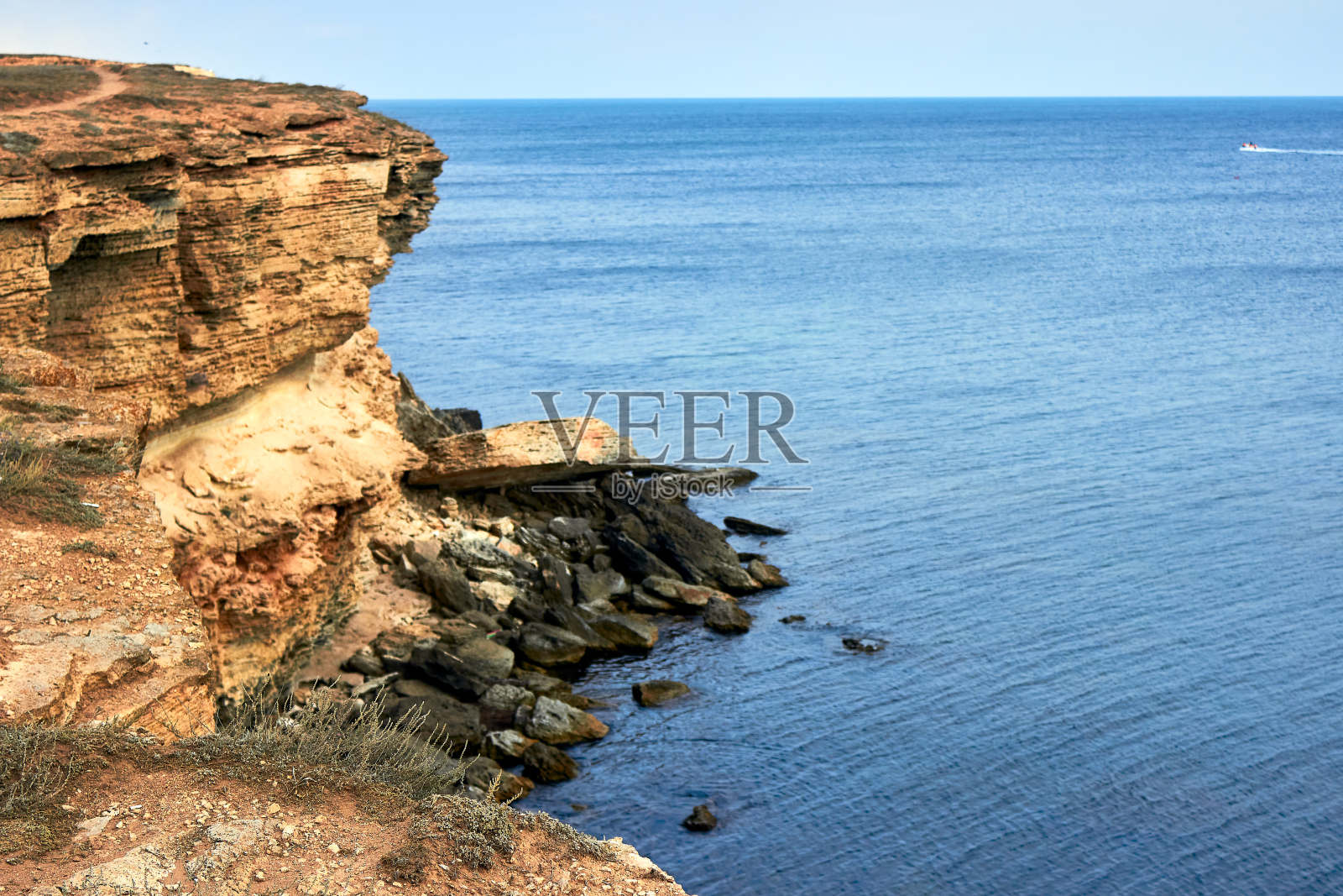 黄色岩石海岸，悬崖。蓝色深沉平静的大海。平静的蓝色的天空。波澜起伏的大海的俯视图。克里米亚西部的塔尔汉库特角。石头的模式。美丽的自然景观。照片摄影图片