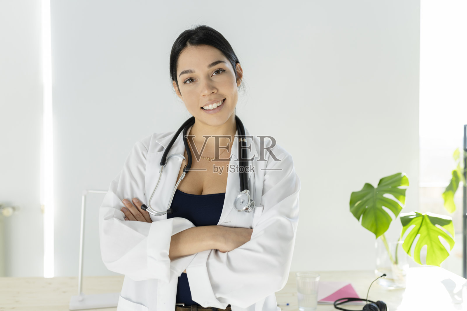 漂亮的拉丁女医生，双臂交叉微笑着照片摄影图片