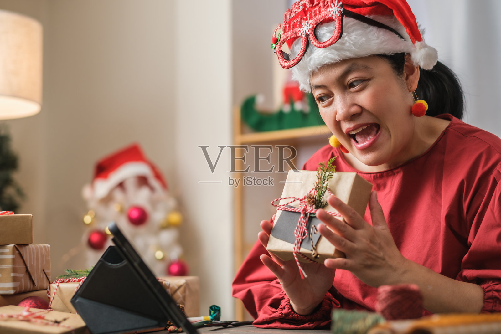 亚洲妇女戴圣诞帽视频电话聚会与朋友与移动电话桌上在家里照片摄影图片