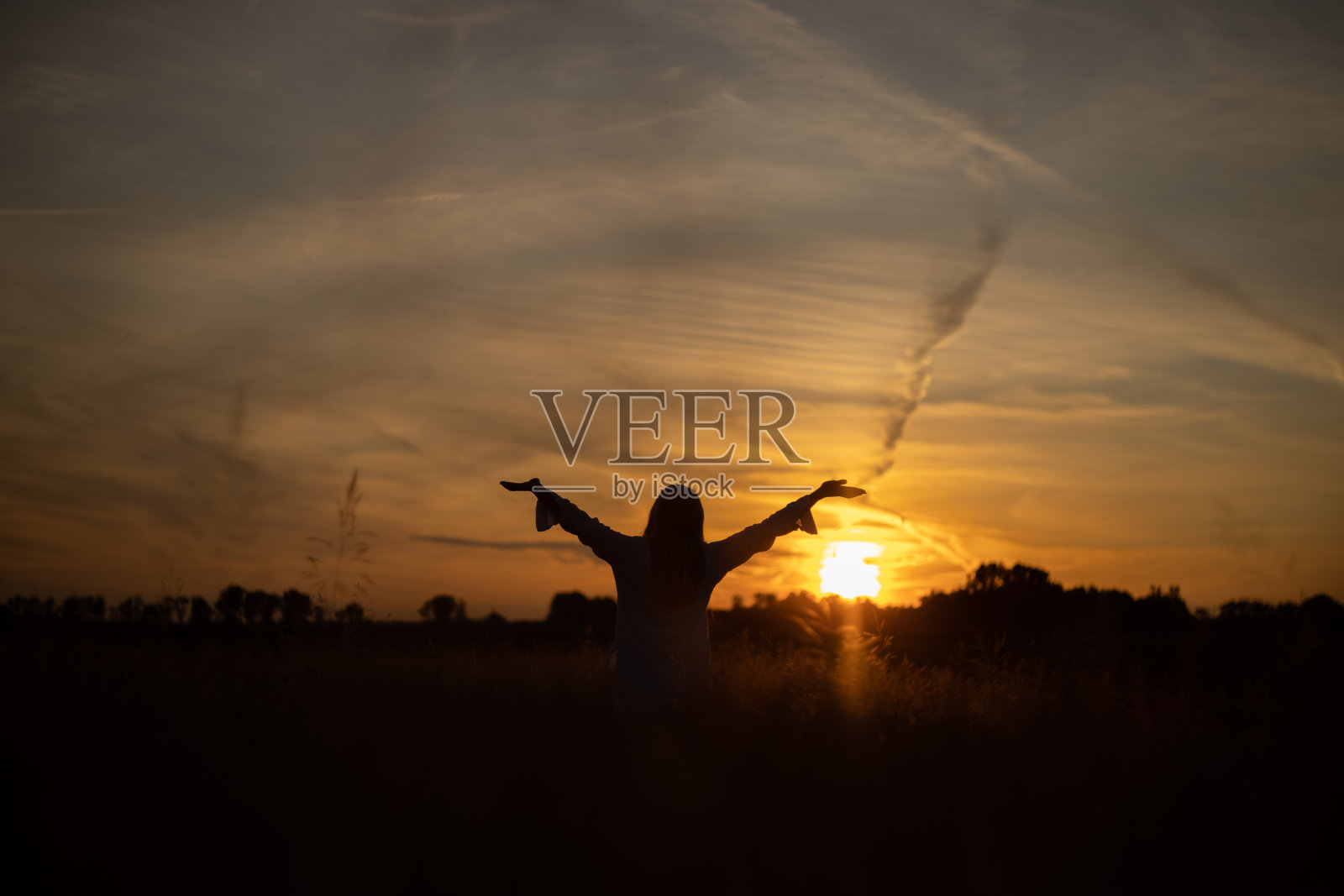 女人站在田野里，享受着夕阳下的大自然照片摄影图片