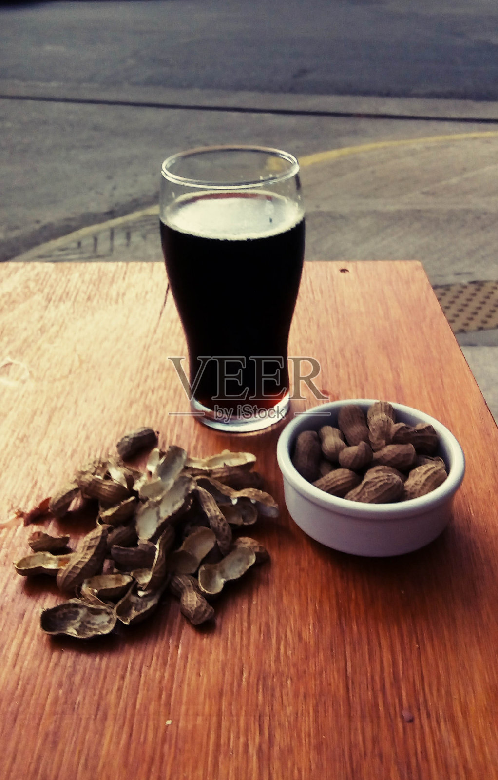 木桌上放着花生的黑色精酿啤酒照片摄影图片