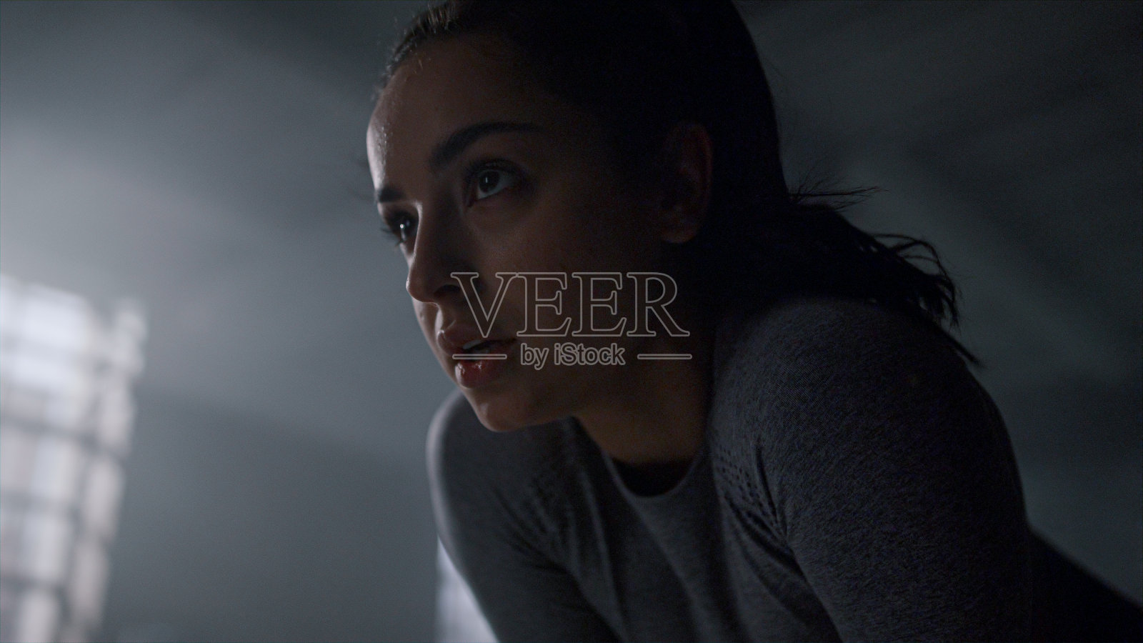 运动后呼吸沉重的女运动员。疲惫的女人站在健身房里照片摄影图片