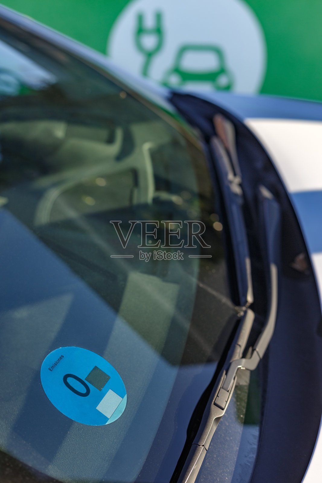 电动汽车在停车场为电动汽车充电。前挡风玻璃上的零排放标签。马德里,西班牙照片摄影图片