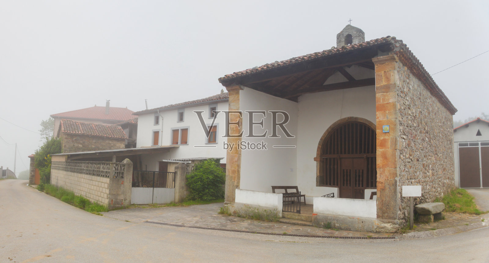 雾中的小村庄教堂。照片摄影图片