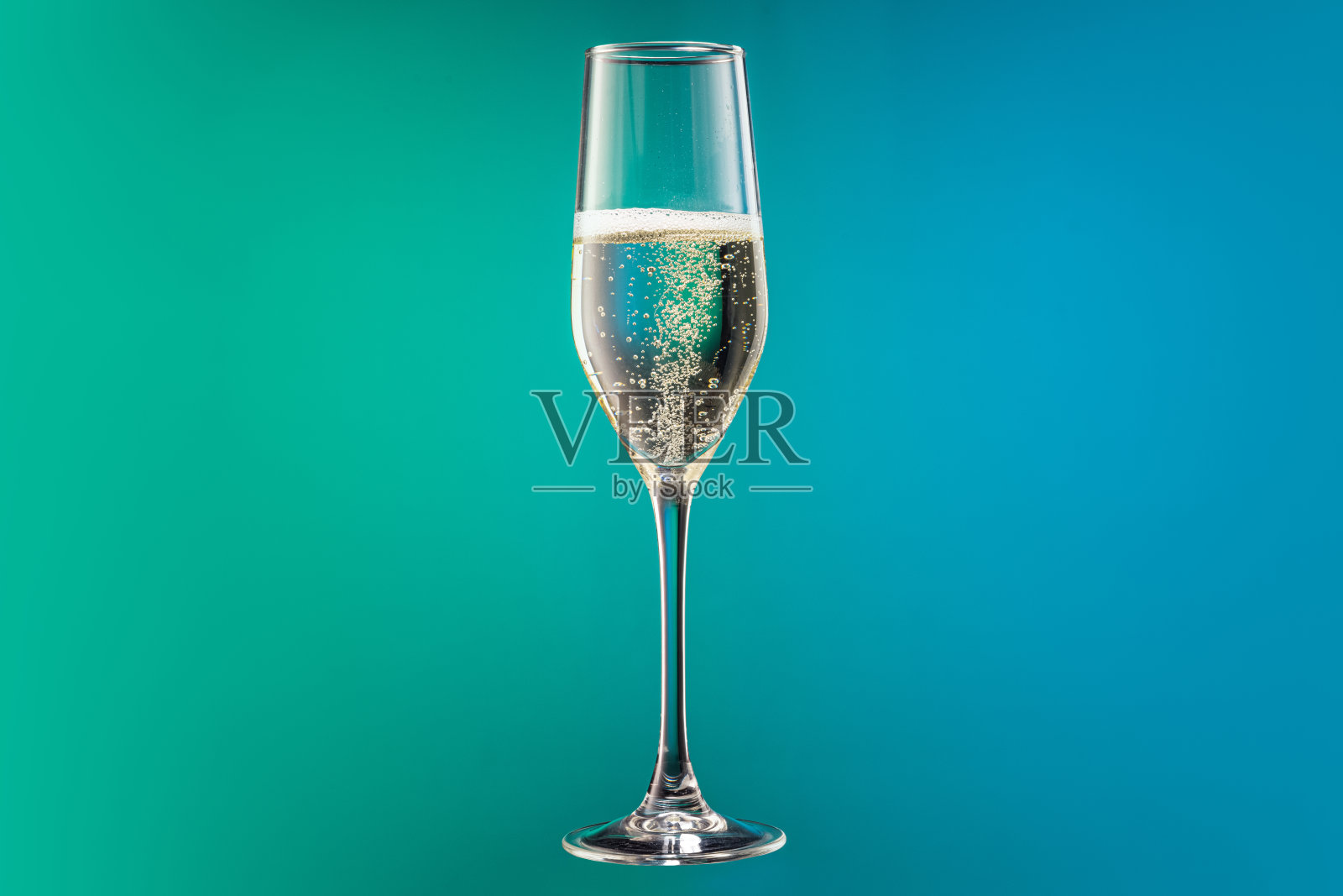 特写玻璃杯与冷香槟气泡隔离梯度蓝色和绿色背景霓虹灯。概念酒，节日，新年照片摄影图片