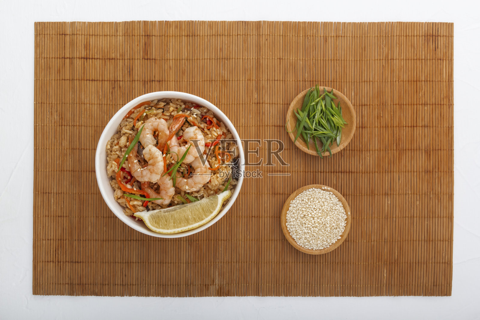 米饭，虾，蔬菜和柠檬放在一次性纸盘的垫上。亚洲街头小吃。从以上观点。照片摄影图片