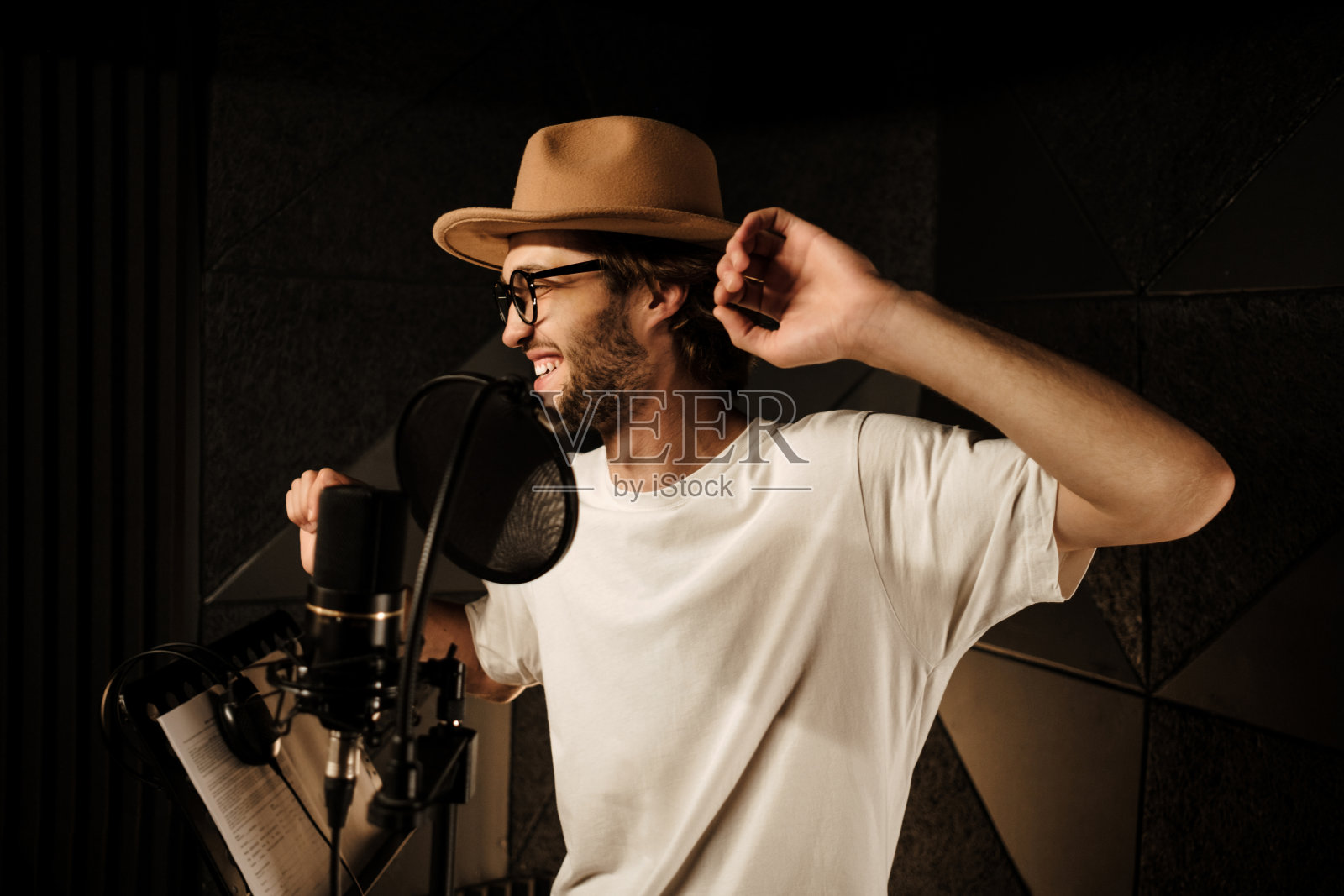 英俊时髦的音乐家愉快地跳舞和唱歌，同时在现代录音室录制新歌照片摄影图片