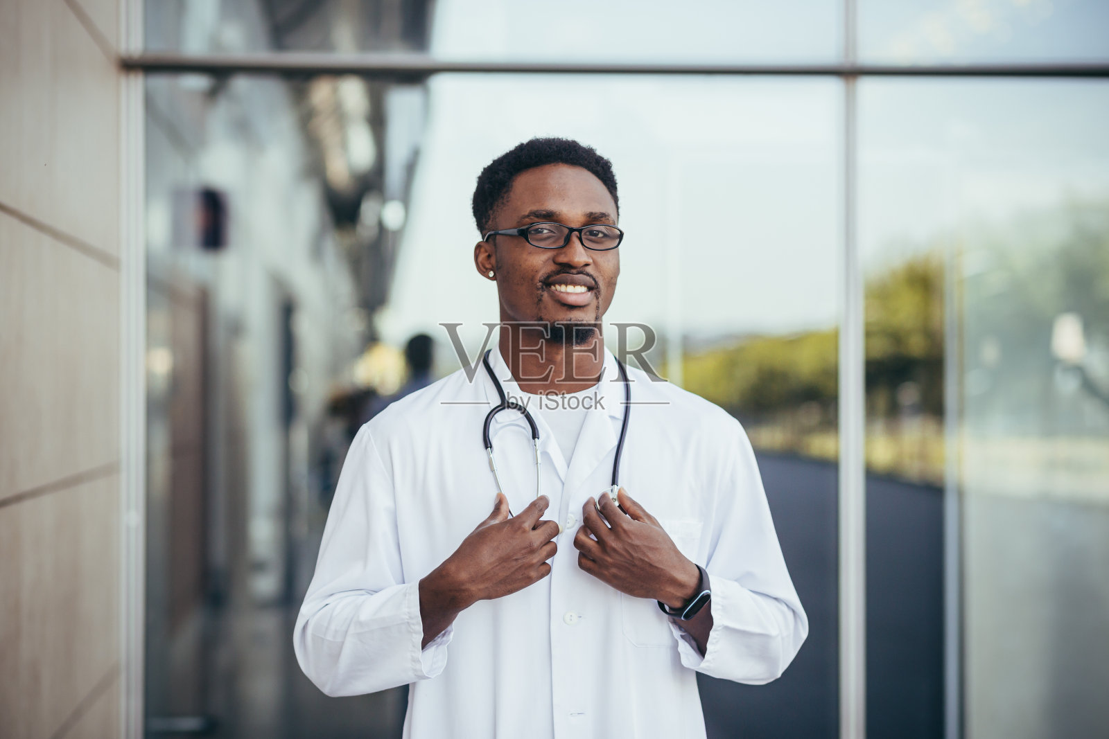 一位非洲医生的肖像，看着相机，微笑着站在诊所前照片摄影图片